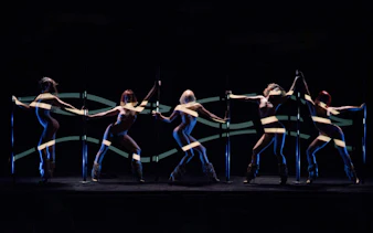 Dancers performing at Crazy Horse Paris show with dynamic lighting effects.