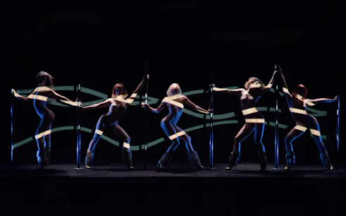 Dancers performing at Crazy Horse Paris show with dynamic lighting effects.