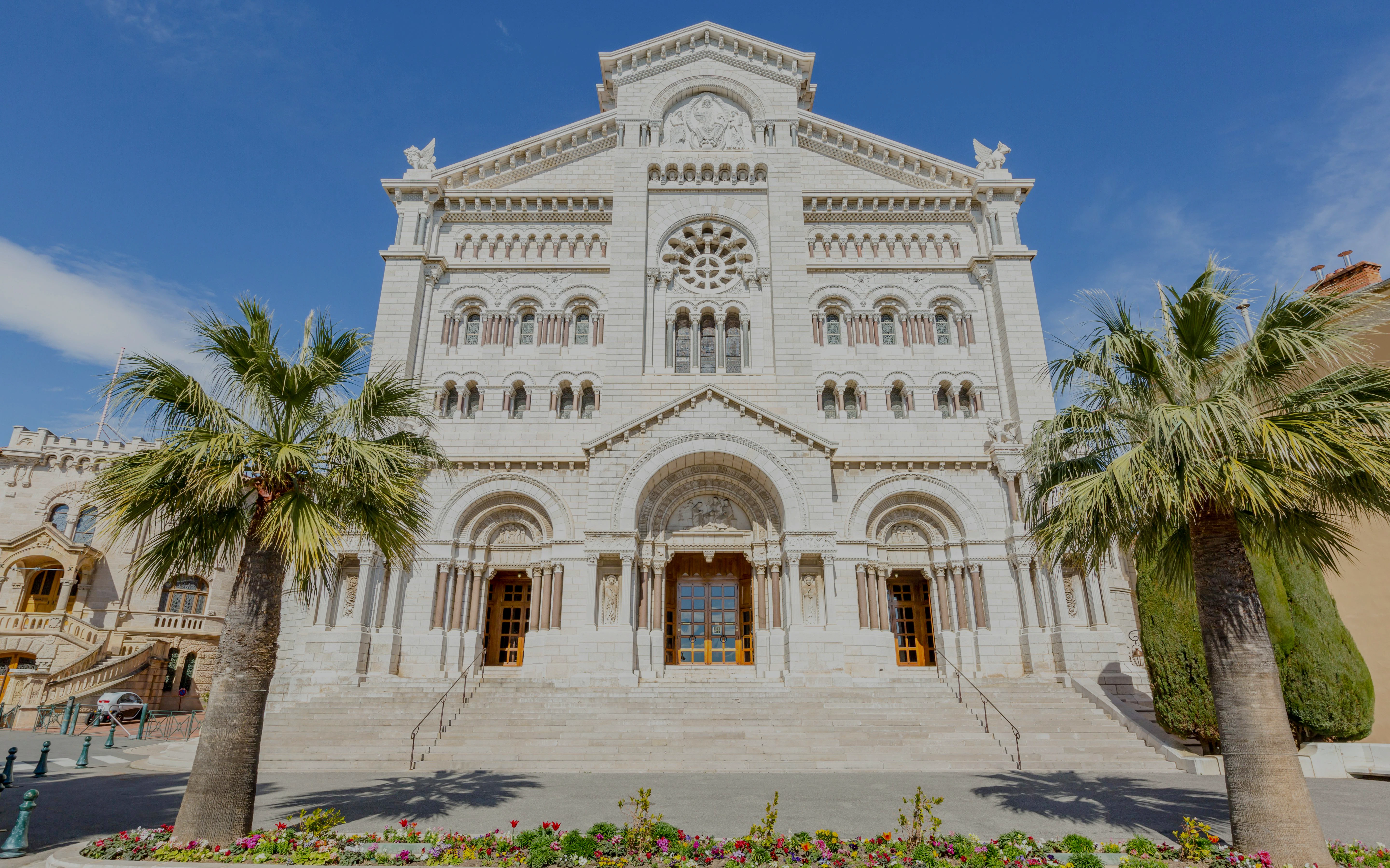 Saint Nicholas Cathedral facade in Monaco with palm trees and clear blue sky.