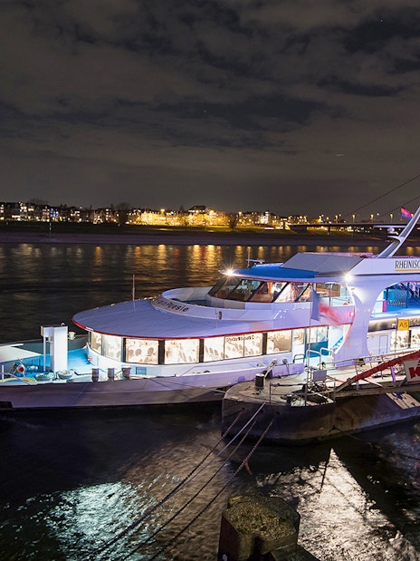 Cruise ship docked at night on the Rhine River in Düsseldorf, decorated for an afternoon advent cruise.