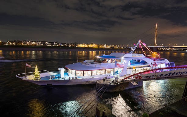 Cruise ship docked at night on the Rhine River in Düsseldorf, decorated for an afternoon advent cruise.
