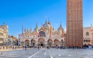 St. Mark's Basilica and Campanile in Venice with tourists in the square.