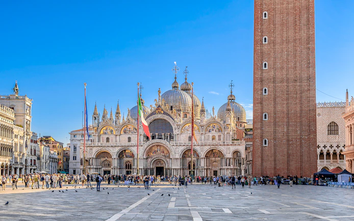 St. Mark's Basilica and Campanile in Venice with tourists in the square.