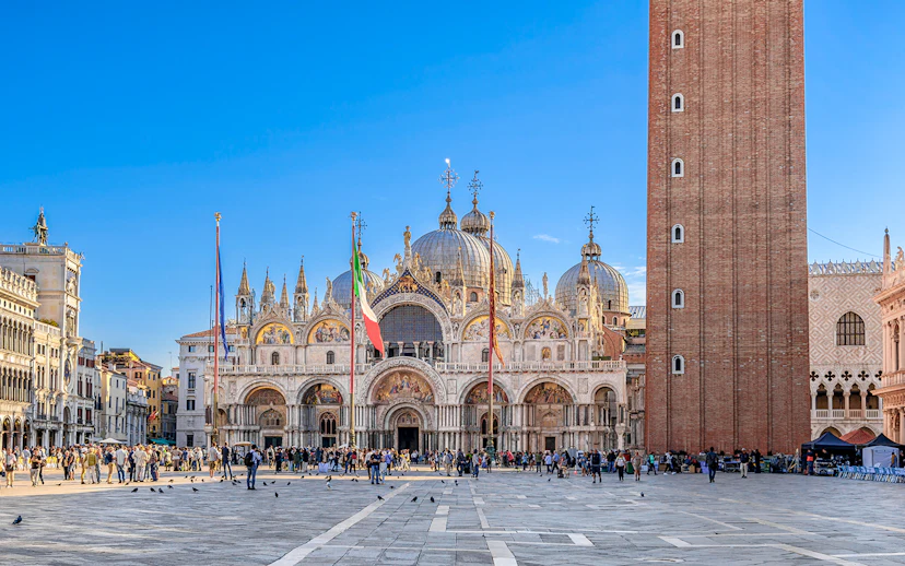 St. Mark's Basilica and Campanile in Venice with tourists in the square.