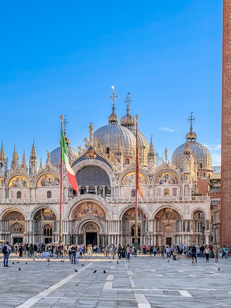 St. Mark's Basilica and Campanile in Venice with tourists in the square.