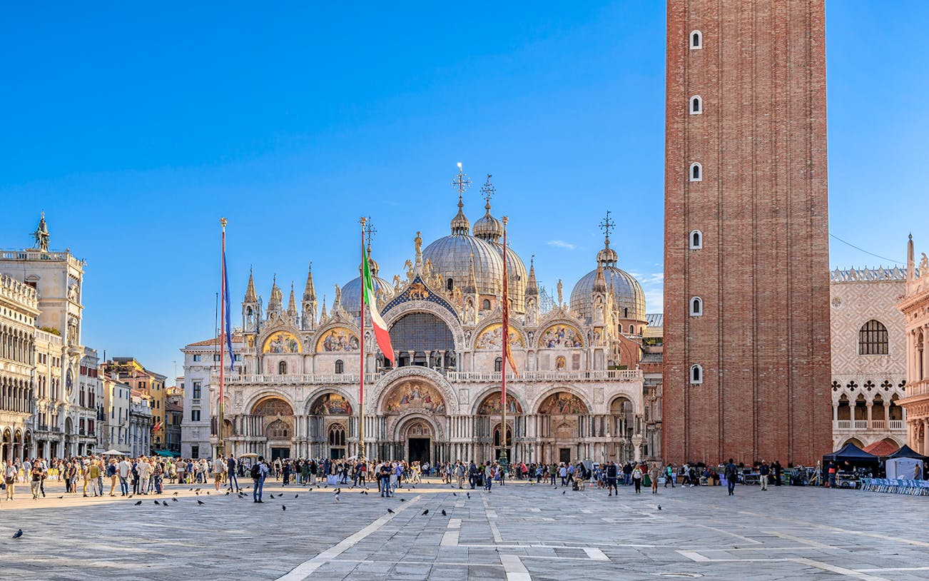 St. Mark's Basilica and Campanile in Venice with tourists in the square.