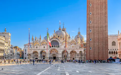 St. Mark's Basilica and Campanile in Venice with tourists in the square.