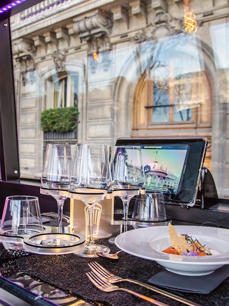 Dining setup inside Bus Toqué Paris with street view through window.