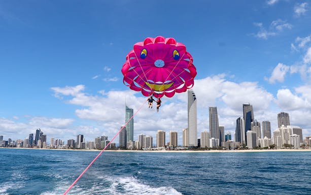 Parasailing over ocean with city skyline in background, Gold Coast, Australia.