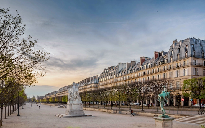 Rue de Rivoli in Paris with historic buildings and statues at sunset.