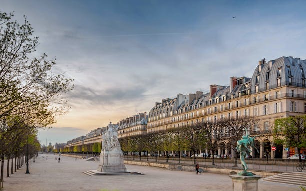 Rue de Rivoli in Paris with historic buildings and statues at sunset.