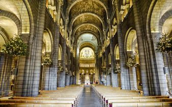 Interior of Cathedral of Monaco with arches and illuminated altar.