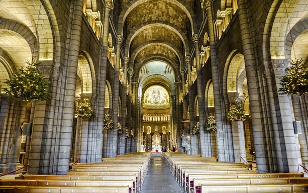 Interior of Cathedral of Monaco with arches and illuminated altar.