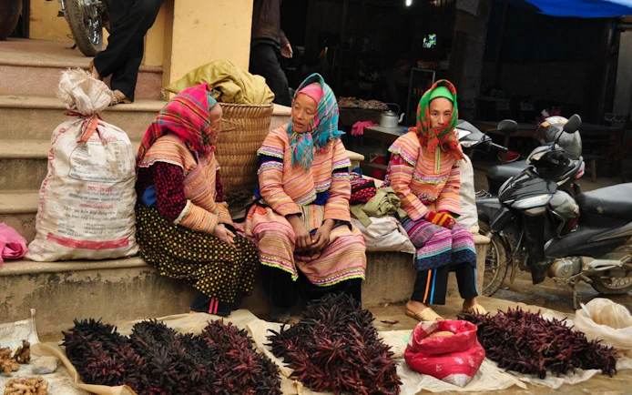 Women in traditional attire selling goods at Bac Ha Market, Vietnam.