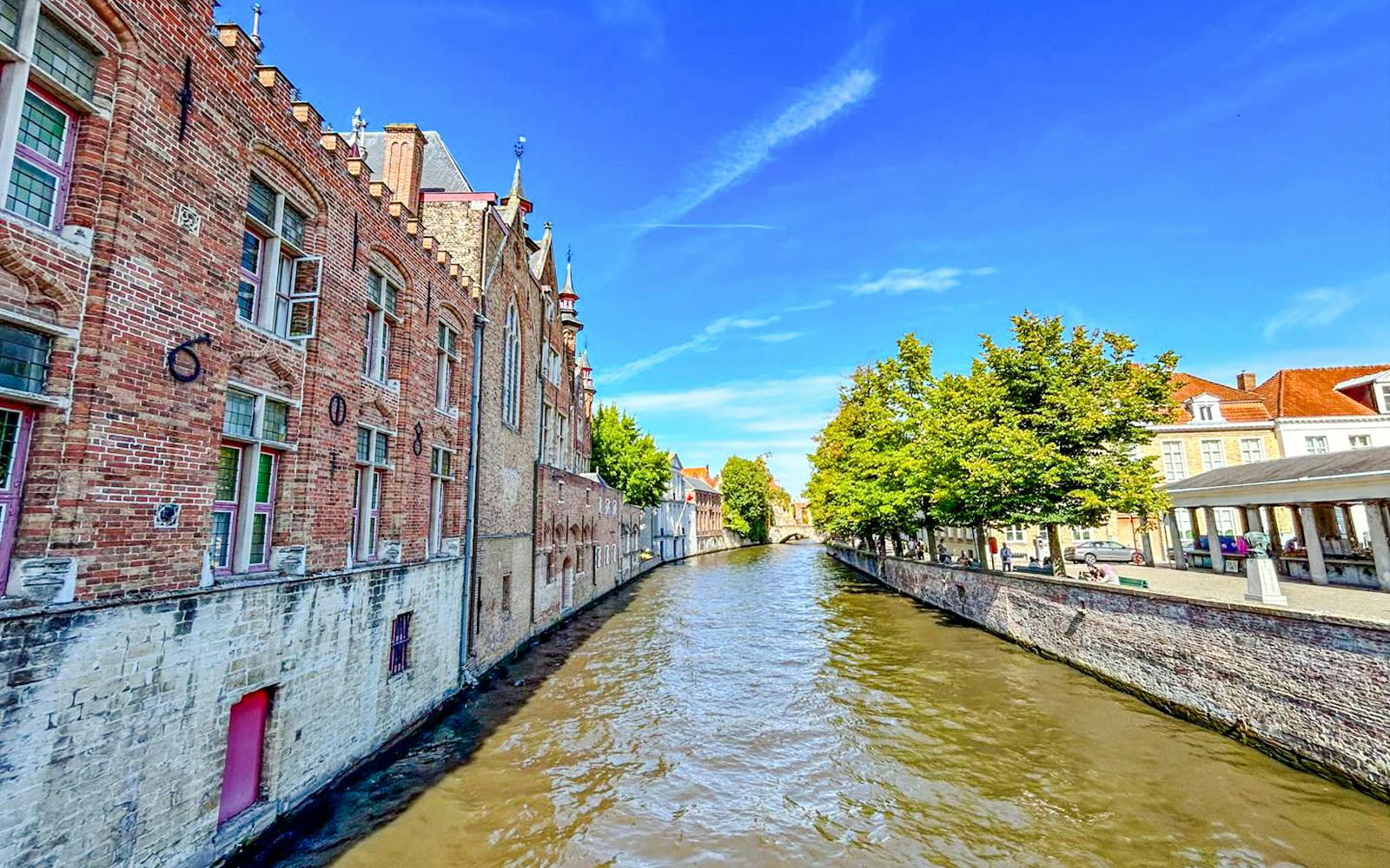 Canal lined with historic buildings and trees in Bruges, Belgium.