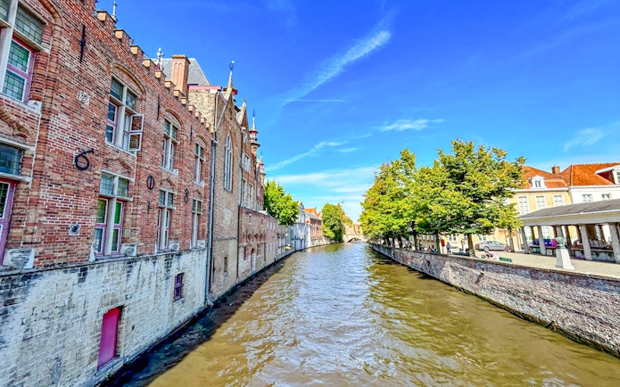 Canal lined with historic buildings and trees in Bruges, Belgium.