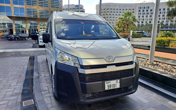 Shuttle bus parked outside a hotel in Dubai for Global Village tour.