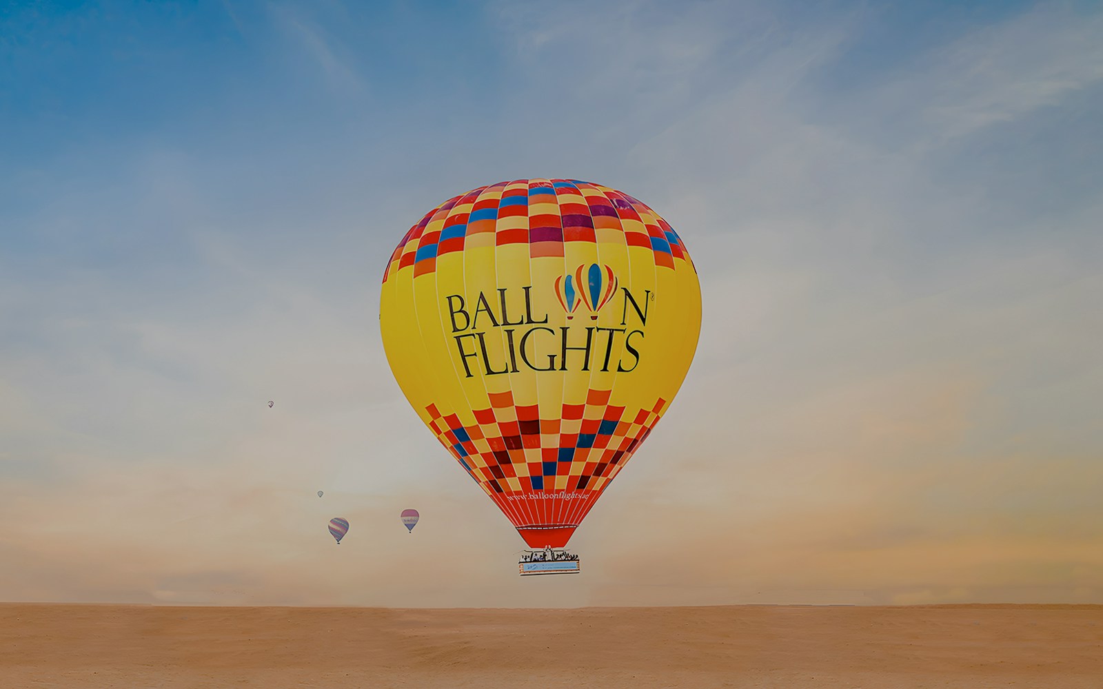 Hot air balloon over Dubai desert with city skyline in background, related to Thames Christmas Party Lunch.