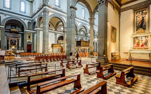 Interior of Basilica di San Lorenzo, Florence, showing columns, pews, and religious artwork.