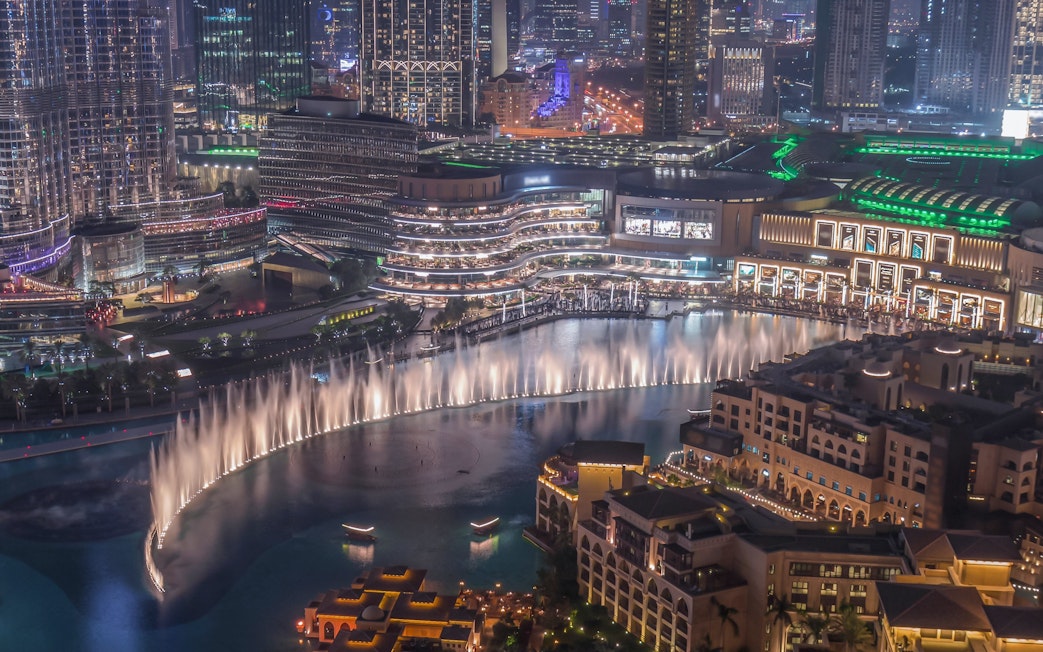 Dubai Canal with illuminated skyline and fountain show at night.