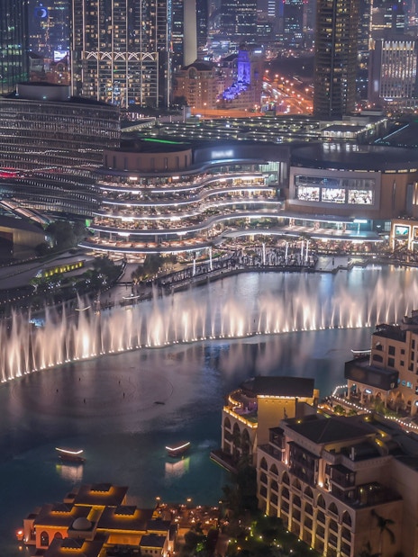 Dubai Canal with illuminated skyline and fountain show at night.