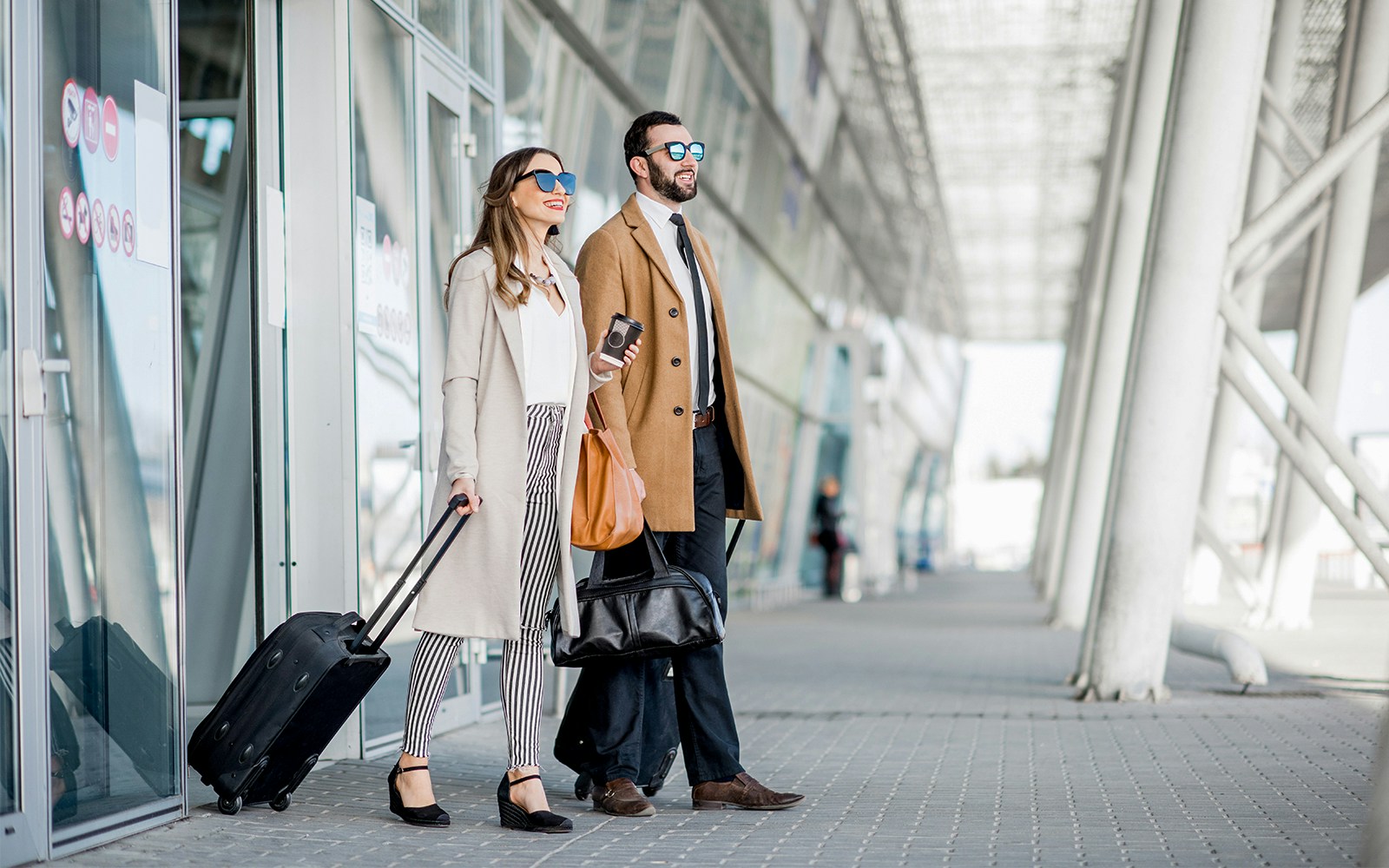 Travelers with luggage outside Bangkok DMK airport for private transfer.