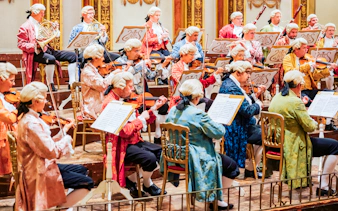 Musicians in period costumes performing at a Mozart Orchestra Concert.