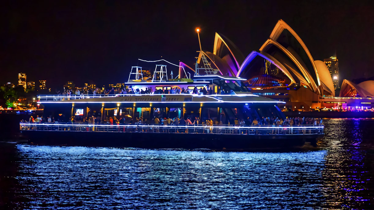 Cruise ship on Sydney Harbour at night with Sydney Opera House in the background.