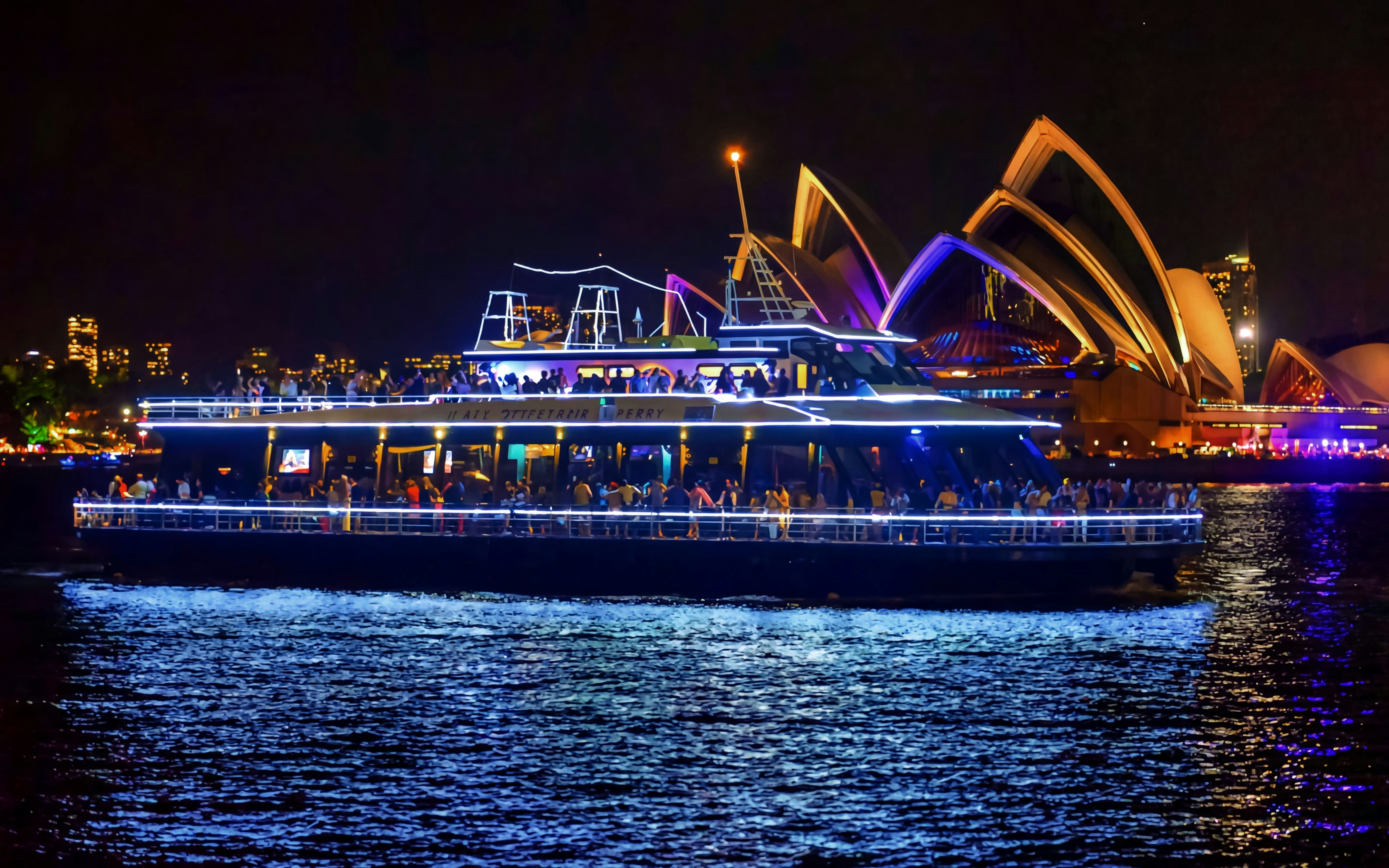 Cruise ship on Sydney Harbour at night with Sydney Opera House in the background.