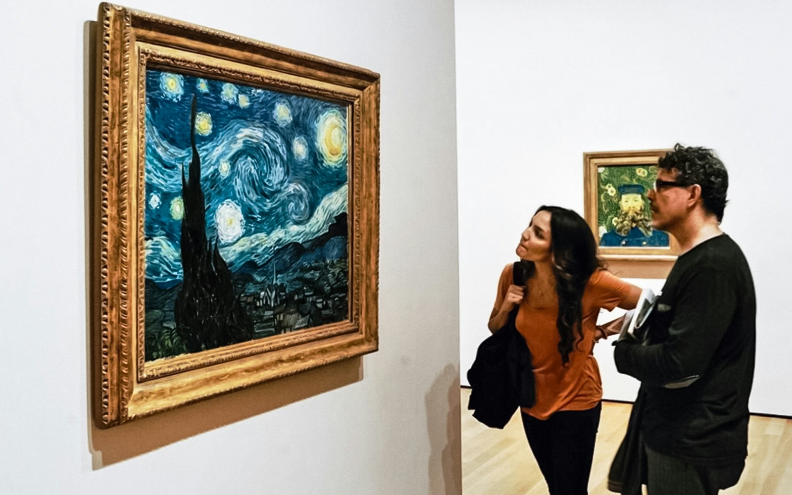 Visitors observing "Starry Night" by Vincent van Gogh in a museum gallery.