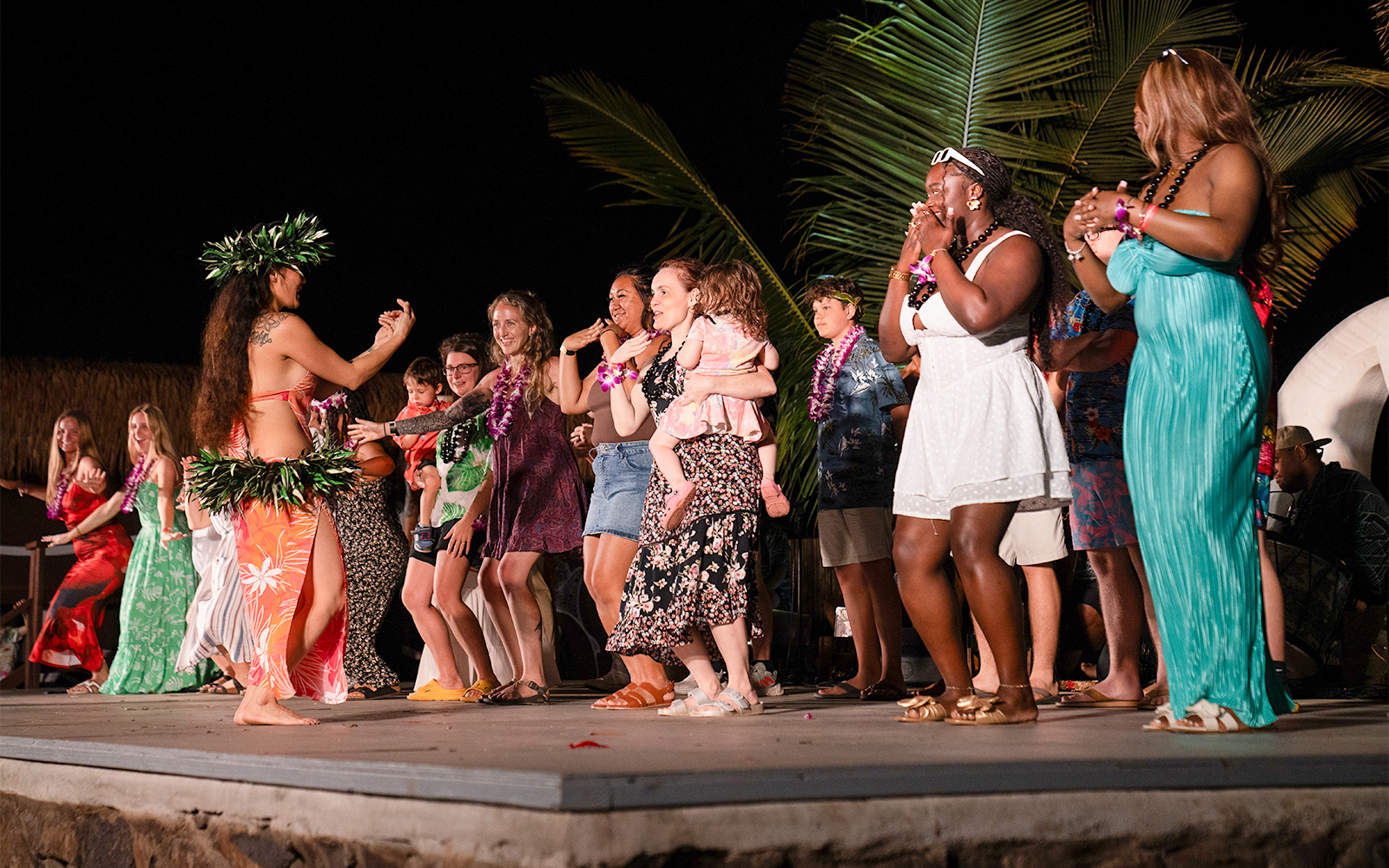 Guests dancing with performers on stage at Mauka Warriors Luau cultural show.