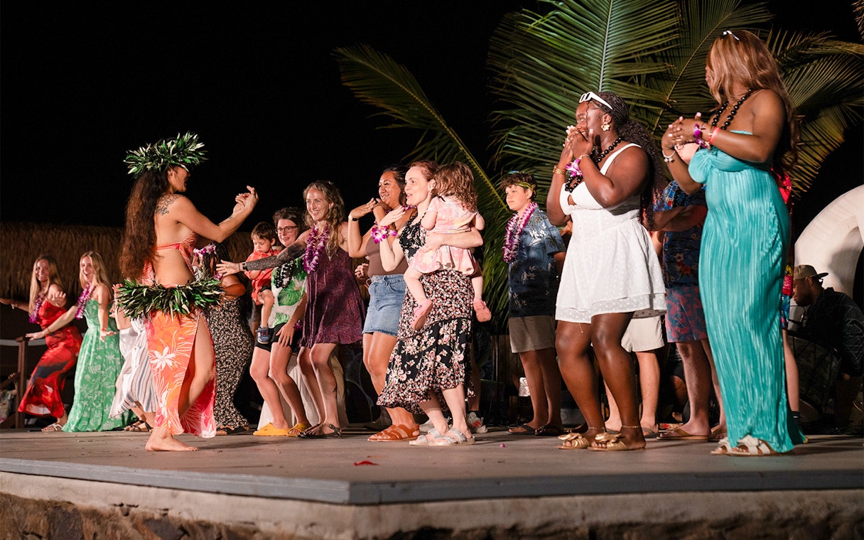 Guests dancing with performers on stage at Mauka Warriors Luau cultural show.