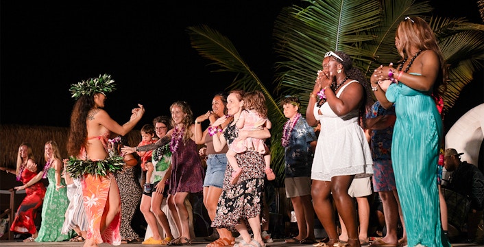 Guests dancing with performers on stage at Mauka Warriors Luau cultural show.