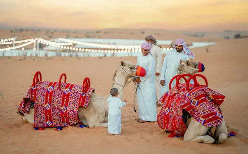 Child petting camel during 57 Heritage Desert Safari in Vintage Land Rover.