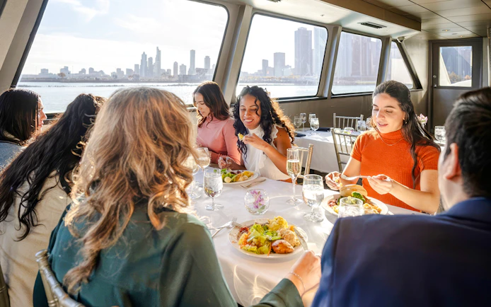 Guests dining on a New Jersey Signature Cruise with city skyline views.