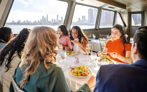 Guests dining on a New Jersey Signature Cruise with city skyline views.
