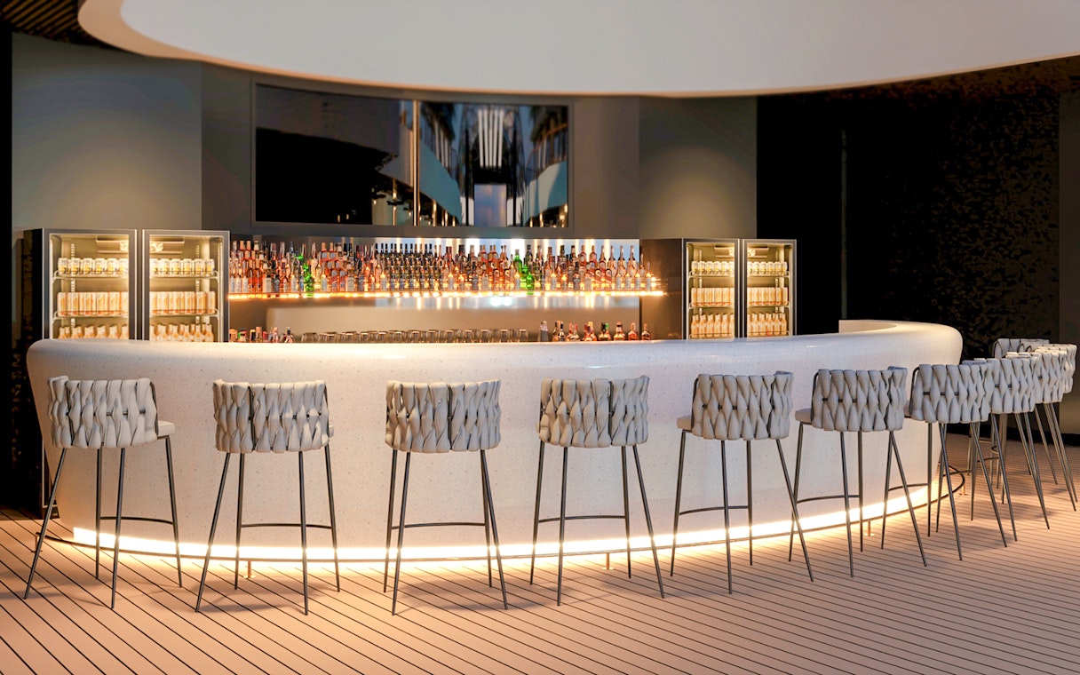 Curved bar counter with stools and illuminated shelves displaying bottles.