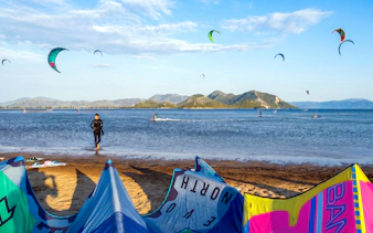 Kiteboarders on the water at Delta Neretva, Croatia with colorful kites in the sky.