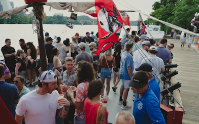 Partygoers on Boomerang Pirate Ship cruise with drinks and DC monuments in background.