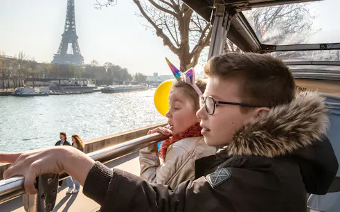 Siblings on Tootbus tour in Paris looking at Seine River with Eiffel Tower in view.
