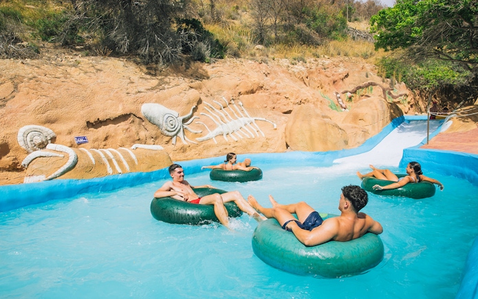 Visitors enjoying a lazy river ride at Aqualandia Benidorm with fossil-themed decor.