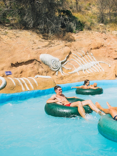 Visitors enjoying a lazy river ride at Aqualandia Benidorm with fossil-themed decor.