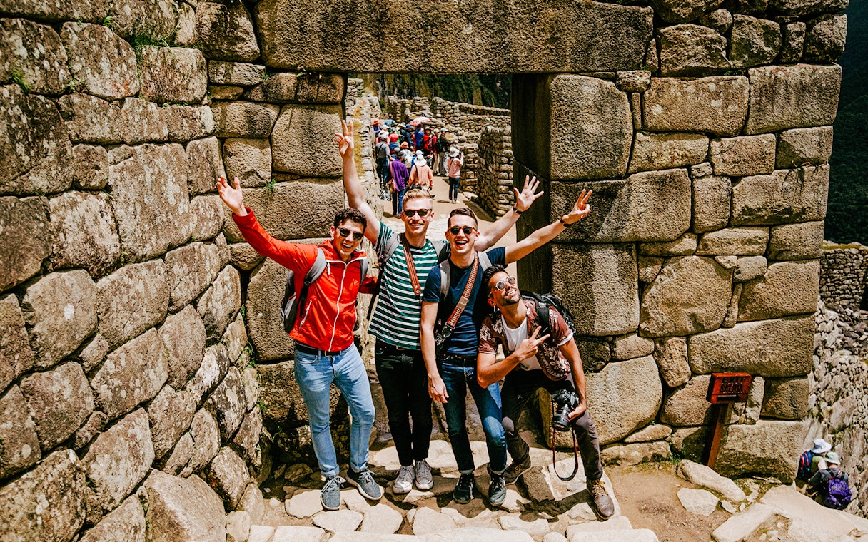Tourists posing at stone entrance in Machu Picchu, Peru.
