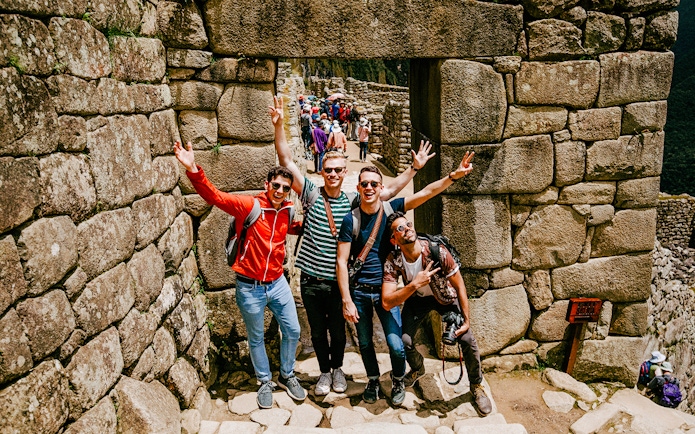 Tourists posing at stone entrance in Machu Picchu, Peru.
