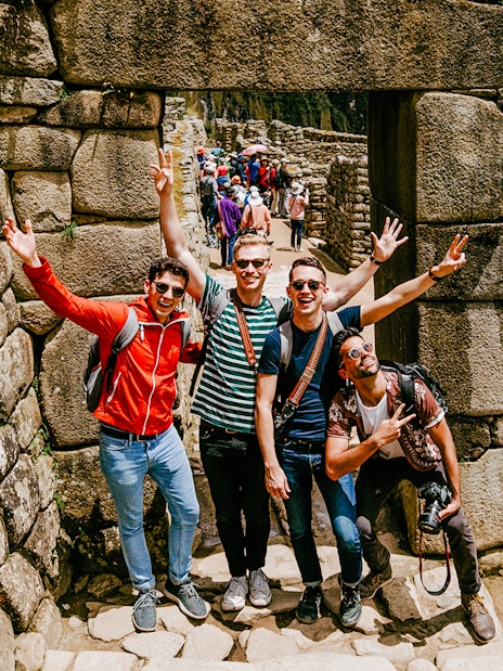 Tourists posing at stone entrance in Machu Picchu, Peru.