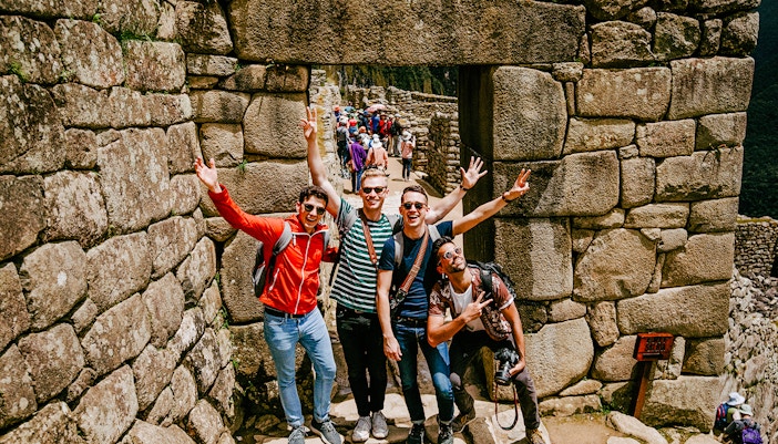 Tourists posing at stone entrance in Machu Picchu, Peru.