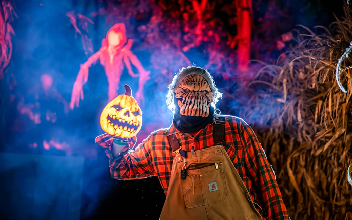 Halloween character holding pumpkin lantern in Dorney Park haunt zone.