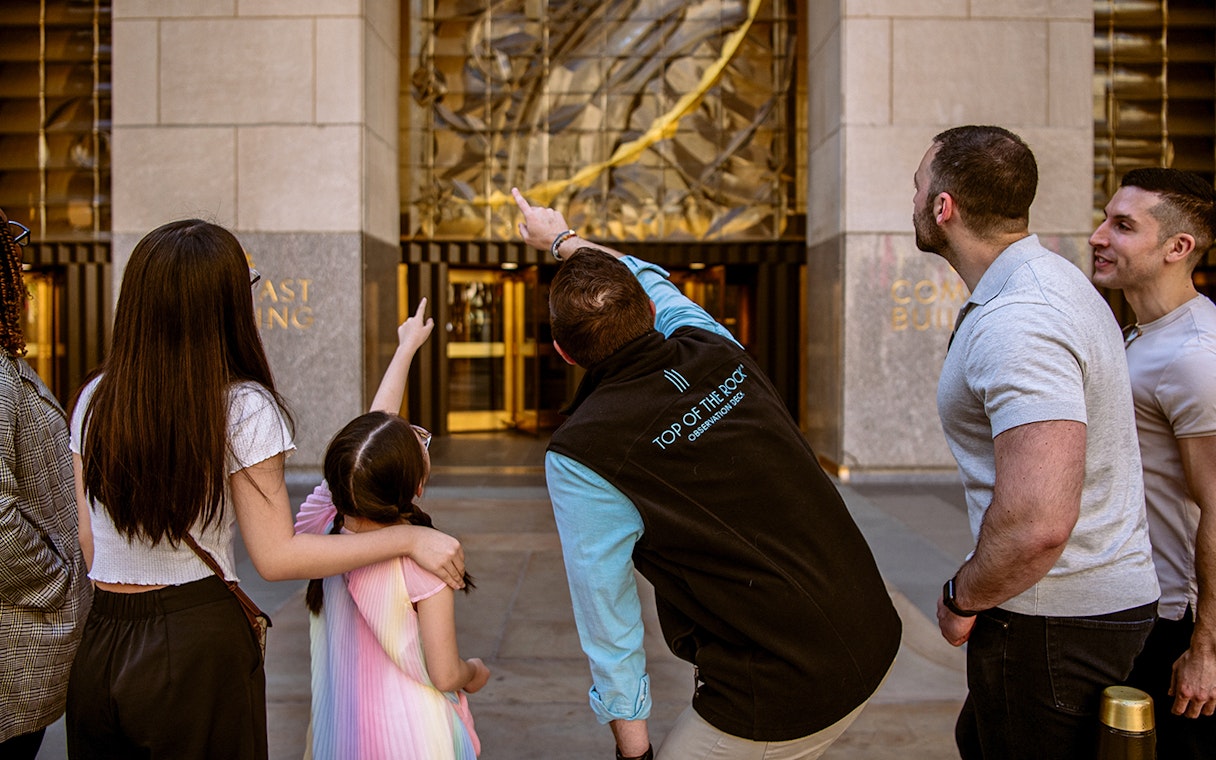 Visitors pointing at the entrance of Top of the Rock Observation Deck in New York City.