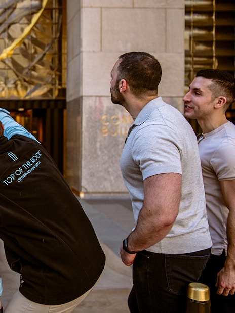 Visitors pointing at the entrance of Top of the Rock Observation Deck in New York City.
