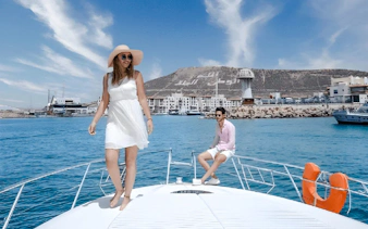 Boat trip with people enjoying the view of Agadir marina and hillside landmark.